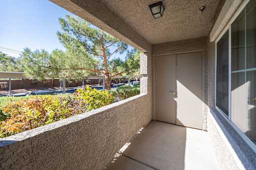 A balcony with a door and a window overlooking a parking lot.