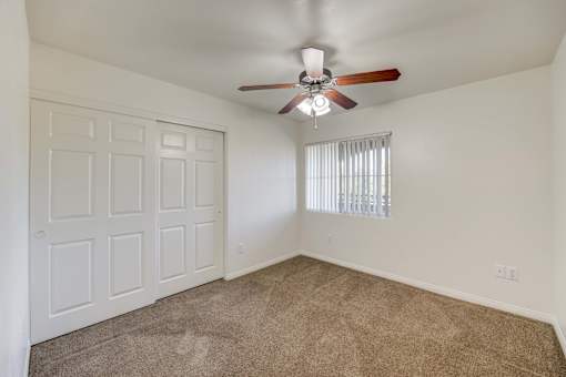 A room with a ceiling fan and a window with blinds.