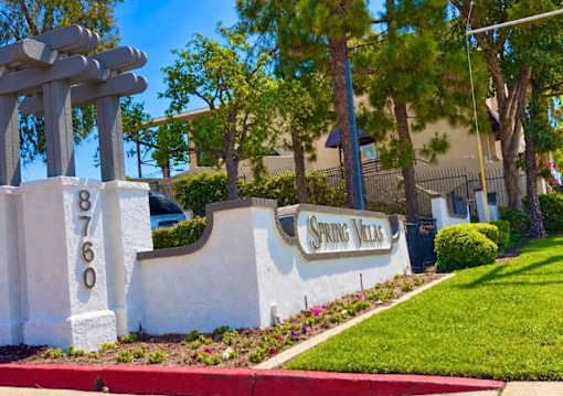 A sign for Spring Villas is displayed in front of a building.
