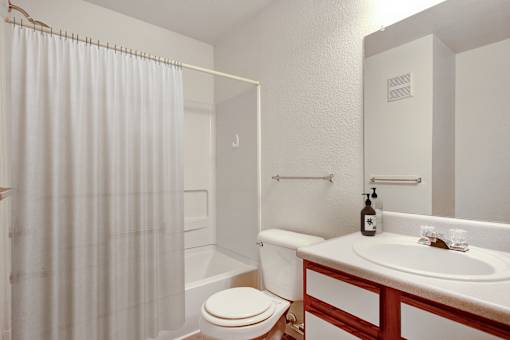 A white bathroom with a toilet, sink, and shower curtain.