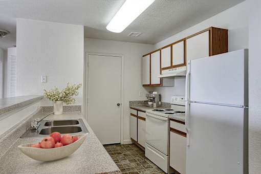 A kitchen with a bowl of apples on the counter.