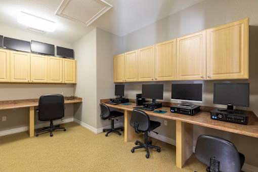 A room with a desk and chairs and a computer.