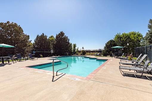 A large swimming pool surrounded by trees and lounge chairs.