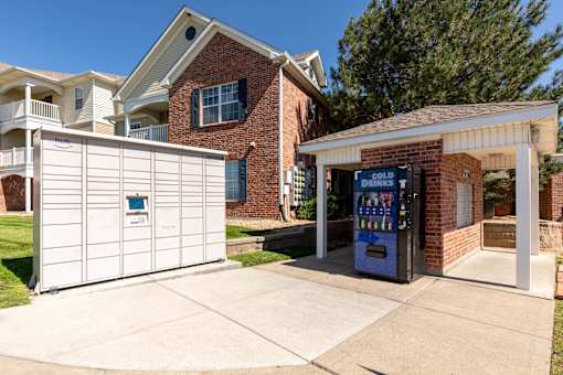 A white garage door is on the left and a brick building with a sign that says Cold Drinks is on the right.