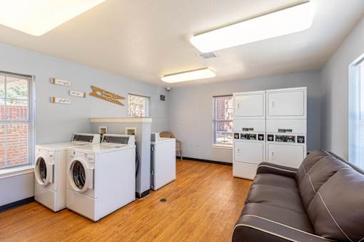 A laundry room with a couch and washing machines.