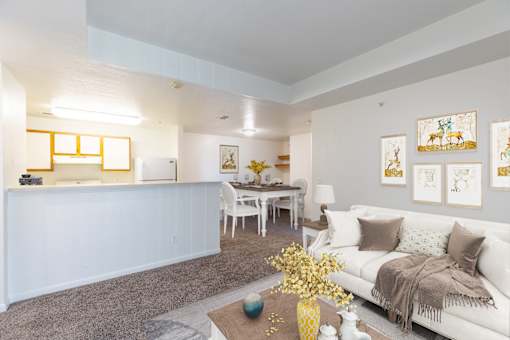 A living room with a white couch and a yellow vase on the coffee table.