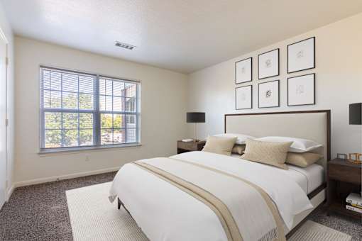 A bedroom with a large bed and a window overlooking a tree-filled area.