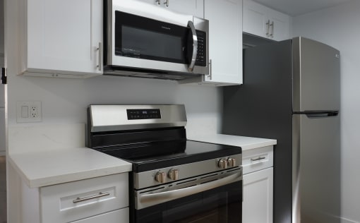 a kitchen with white cabinets and a stove and a microwave