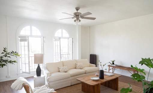 A living room with a white couch, a wooden coffee table, and a ceiling fan.