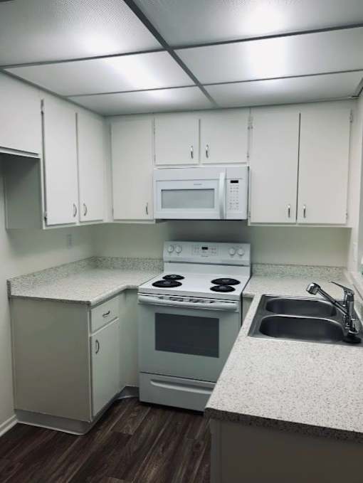 A kitchen with white cabinets and a white microwave above the stove.
