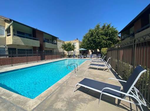 A pool surrounded by chairs and a fence.