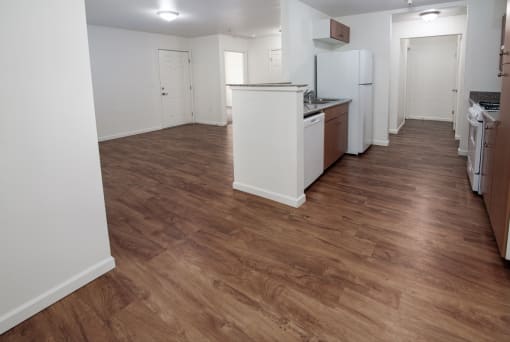 an empty kitchen with a wooden floor and white appliances
