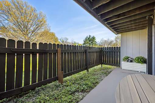 A wooden fence with a grey railing and a grey bench.