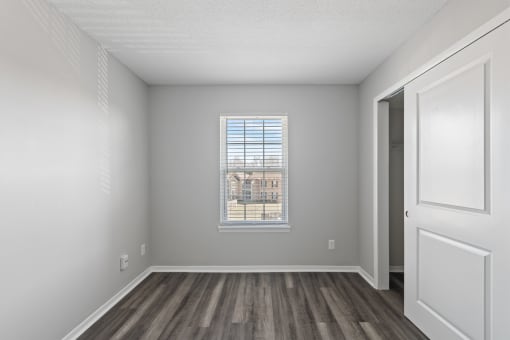 an empty living room with wood flooring and a window