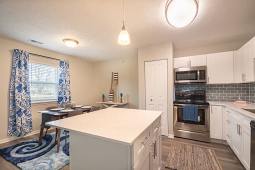 a kitchen with white cabinets and a white island with a blue and white rug