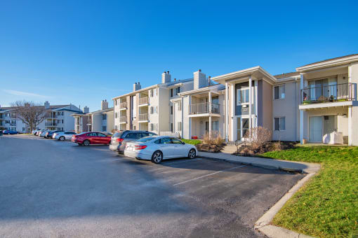 a row of apartment buildings with cars parked in front of them