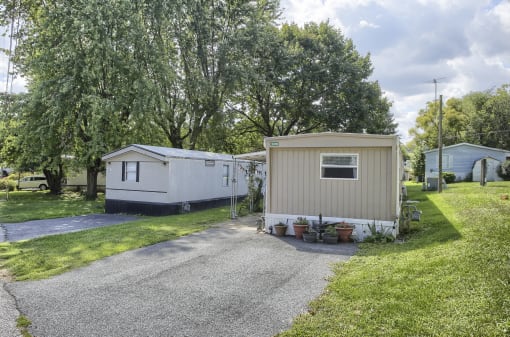 a mobile home is parked on a gravel driveway in a grassy area with trees in the