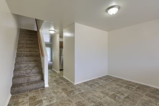an empty living room with a staircase in a house with white walls