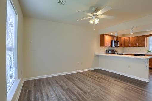 A room with a ceiling fan and a counter with a microwave.