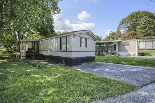 a mobile home is parked in a grassy area with a gravel driveway