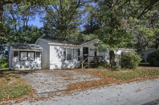 a house with a driveway and trees in the background