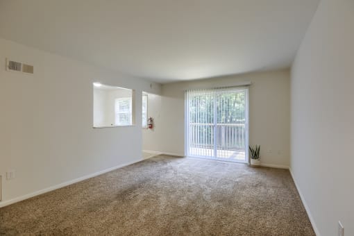 an empty living room with a sliding glass door and carpeting