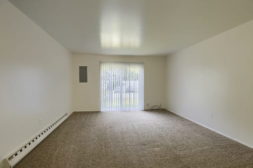 an empty room with carpet and a sliding glass door