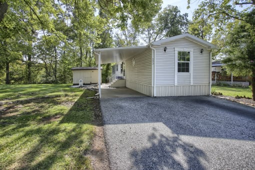 a white house with a gravel driveway and a white carport