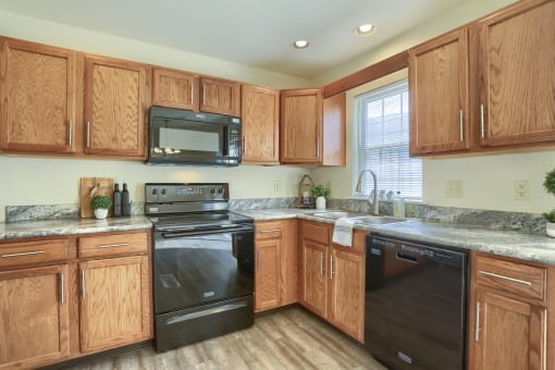 Mechanicsburg Apartments | Rockledge Townhomes |  a kitchen with wood cabinets and black appliances