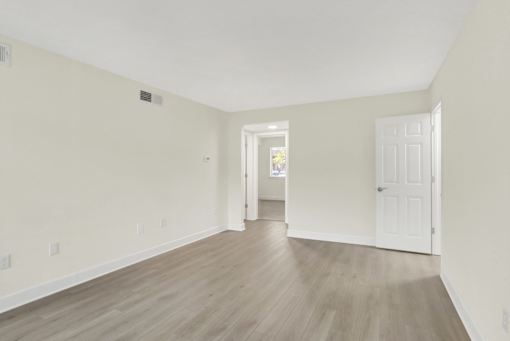 A room with light wood flooring and white walls.