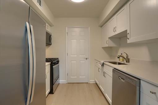 A kitchen with a stainless steel refrigerator and white cabinets.