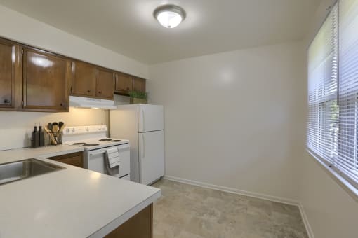 an empty kitchen with white appliances and a large window