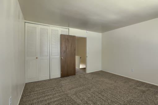 an empty living room with carpet and white closet doors