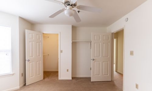 A room with a ceiling fan and three doors.