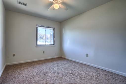 A room with a ceiling fan and a window.