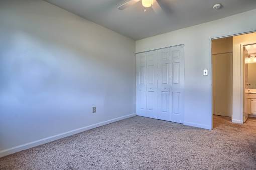 A room with a carpeted floor and a ceiling fan.