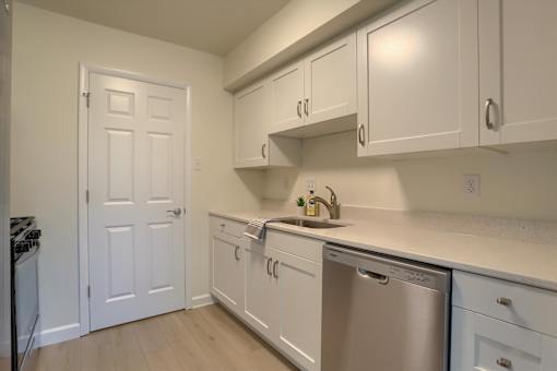 A kitchen with white cabinets and a stainless steel dishwasher.