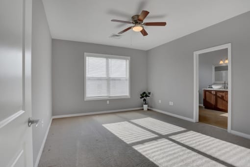 a bedroom with a ceiling fan and a doorway into a bathroom | Centerpointe Apartments in Camp Hill