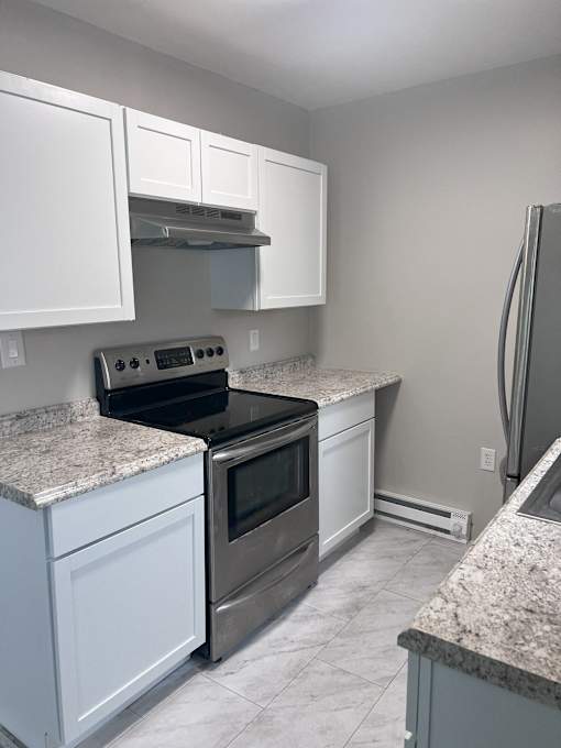 A kitchen with white cabinets and granite countertops.