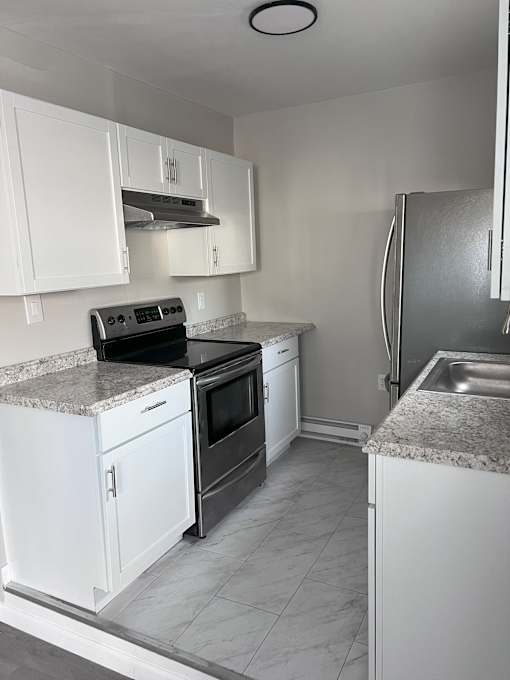 A kitchen with white cabinets and a granite countertop.