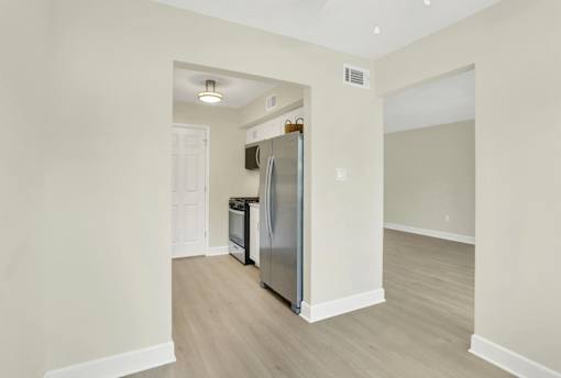 A kitchen with a refrigerator, dishwasher, and a white door.