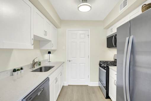 A kitchen with white cabinets and a black fridge.