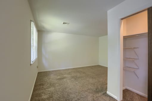 an empty bedroom with a closet and a window