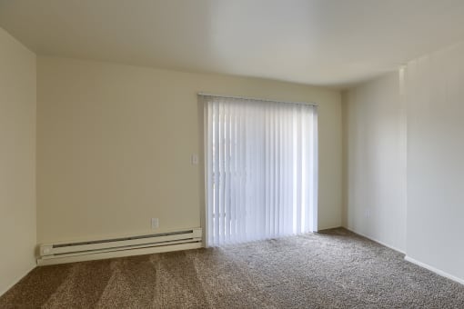 a living room with a window and a carpeted floor