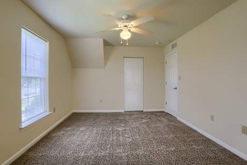 A room with a ceiling fan and carpeted floor.