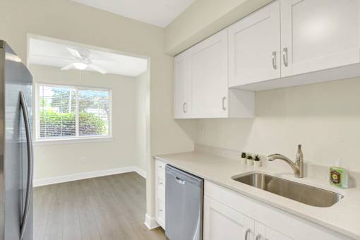 A kitchen with a refrigerator, dishwasher, and a sink.