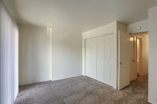 an empty room with white walls and a door to a closet