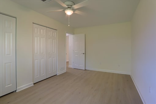 A room with a ceiling fan and wooden flooring.