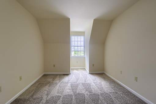 A room with a carpeted floor and a window.