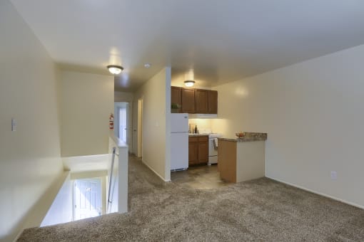 a living room and kitchen with carpeted floors and white walls